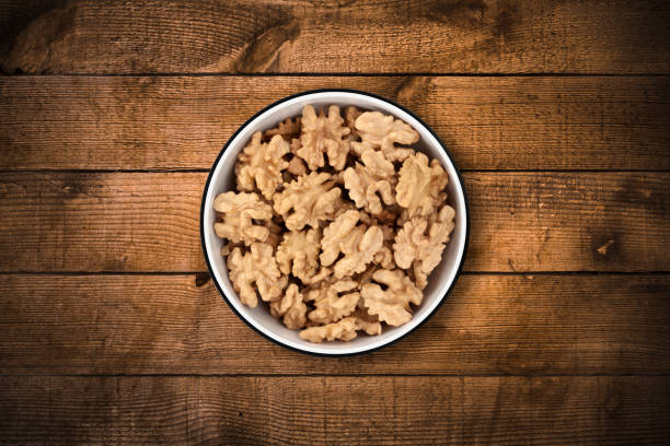 Shelled walnuts in a circle bowl on a rustic old wood background, shot from directly above. Clipping path included.