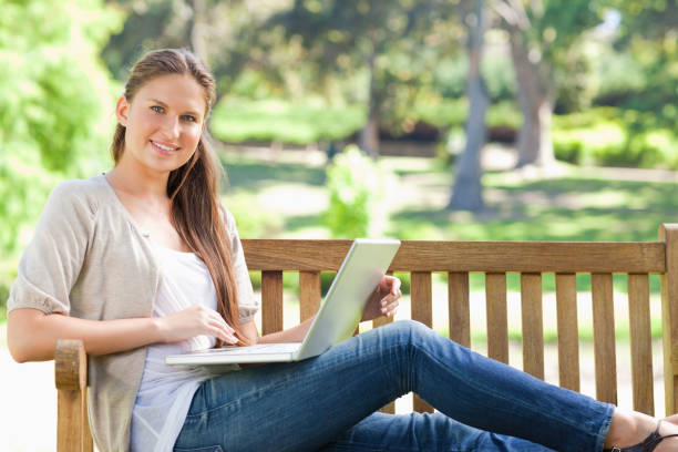 istock Smiling woman with her laptop on a park bench 842153274