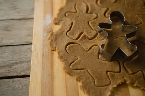High angle view of gingerbread man pastry cutter on dough over cutting board