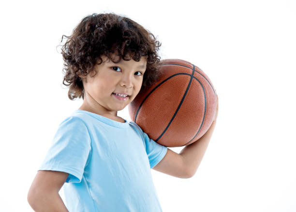 istock Young boy holding a basketball against white background 842155690