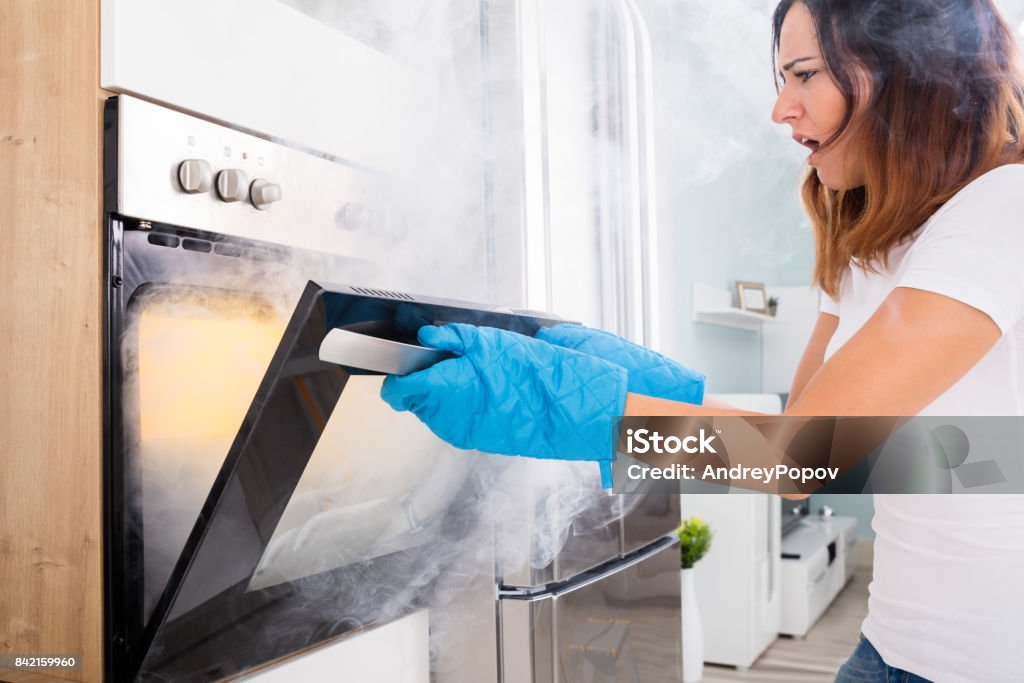 Woman Opening Door Of Oven Full Of Smoke Young Unhappy Woman Opening Door Of Oven With Full Of Smoke Food Stock Photo