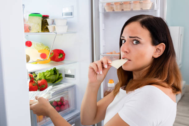 istock Woman Eating Cheese In Front Of Refrigerator 842163036