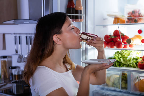 istock Woman Eating Cake In Front Of Refrigerator 842163310