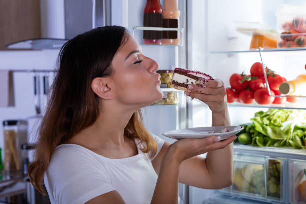 istock Woman Eating Cake In Front Of Refrigerator 842163468