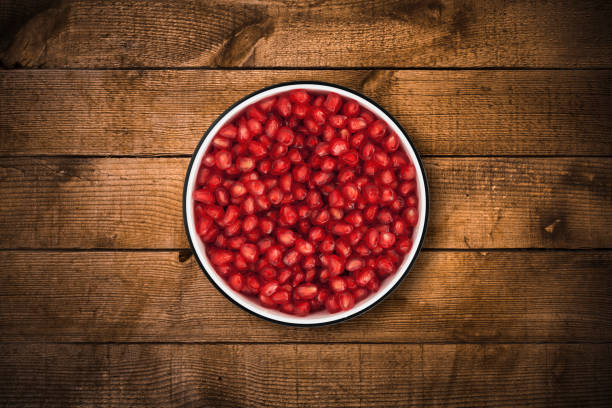 istock Pomegranate seeds bowl on wood background from directly above 842163596