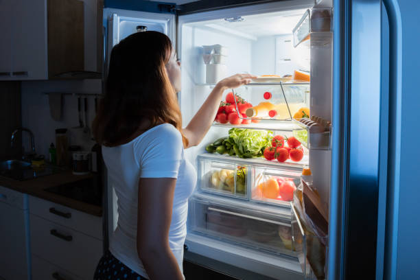 femme regardant les aliments au réfrigérateur - frigo ouvert photos et images de collection