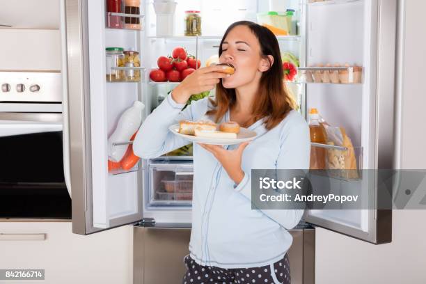 Woman Eating Sweet Food Near Refrigerator Stock Photo - Download Image Now - Eating, Hungry, Pregnant