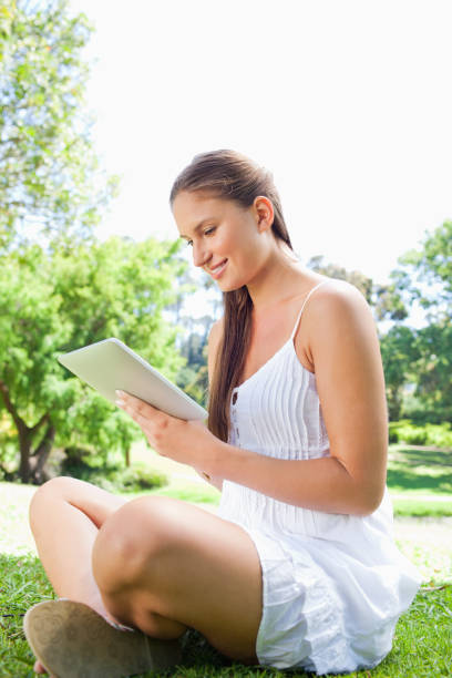 istock Side view of a smiling woman using a tablet computer in the park 842174082