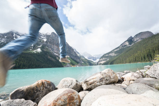 istock Hiker jumps rock to rock on mountain lake 842183670