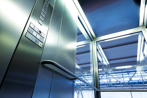 Interior metal y vidrio elevador en edificio moderno, botones brillantes y pasamanos photo