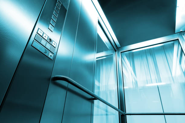 A senior Caucasian male executive, in professional attire, is correcting his tie inside a sleek, glass-paneled elevator of a contemporary office building.