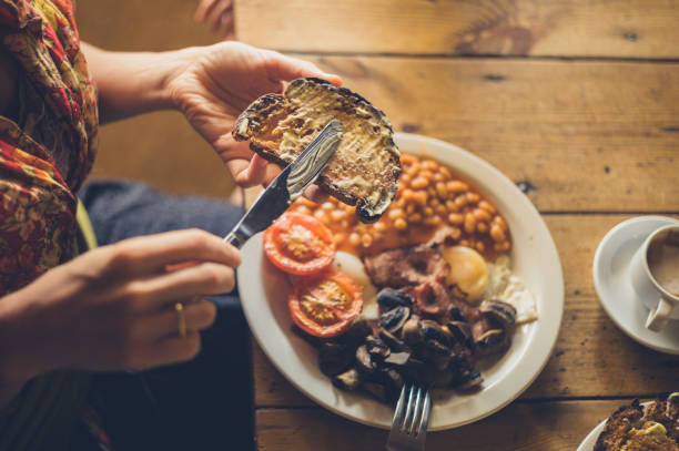 Young woman spreading butter on toast as part of a traditional english breakfast