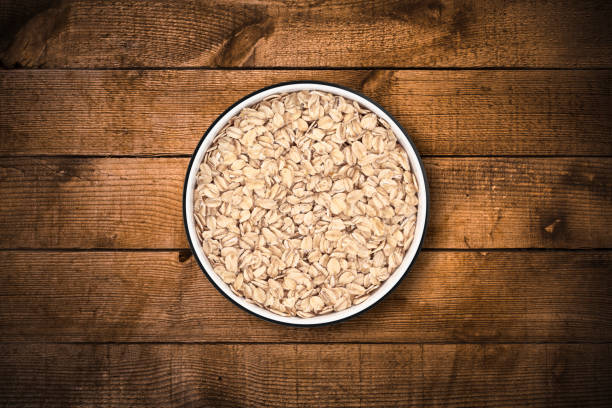 Oat flakes in circle bowl on a rustic old wood background, shot from directly above. Clipping path included.