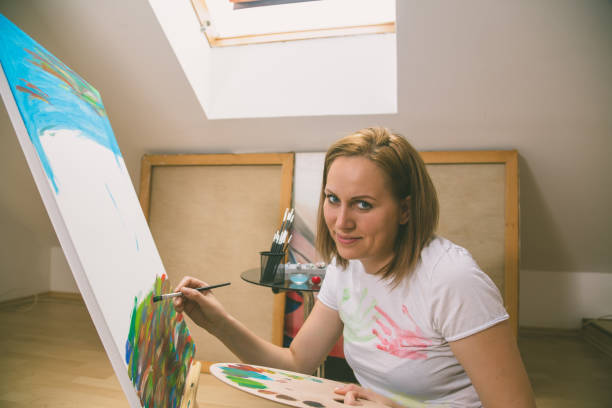 istock Happy young woman paints on canvas 842206844