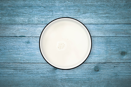Milk in a circle bowl on a rustic old wood background, shot from directly above.