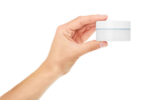 istock female hand holding cream in container. Isolated on white background 842209374