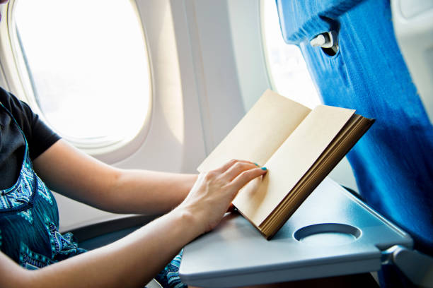 istock Young woman reading a book in airplane 842210012