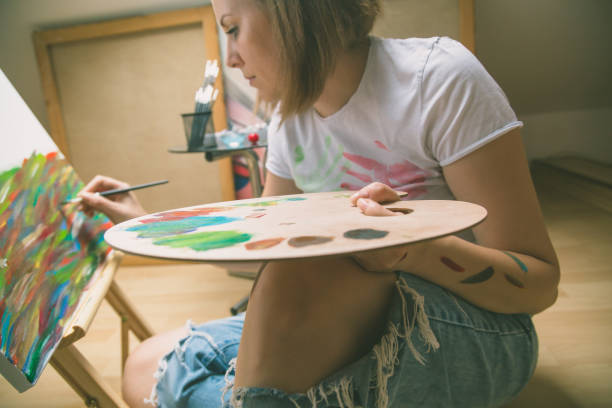 istock Happy young woman paints on canvas 842210358