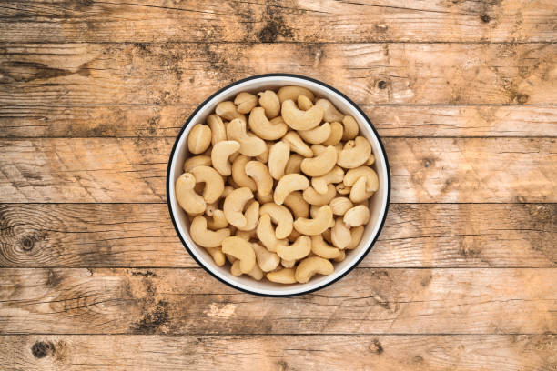 Shelled cashews in a circle bowl on a rustic old wood background, shot from directly above. Clipping path included.
