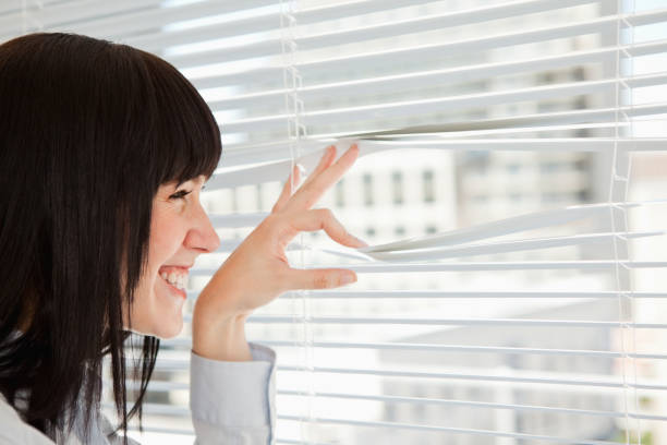 istock Smiling woman looks out through her blinds 842213630