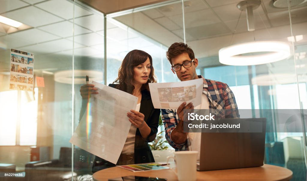 Young designers working together on a creative project Young designers working together at office desk. Business professionals looking at pictures for their new design project. Travel Agency Stock Photo