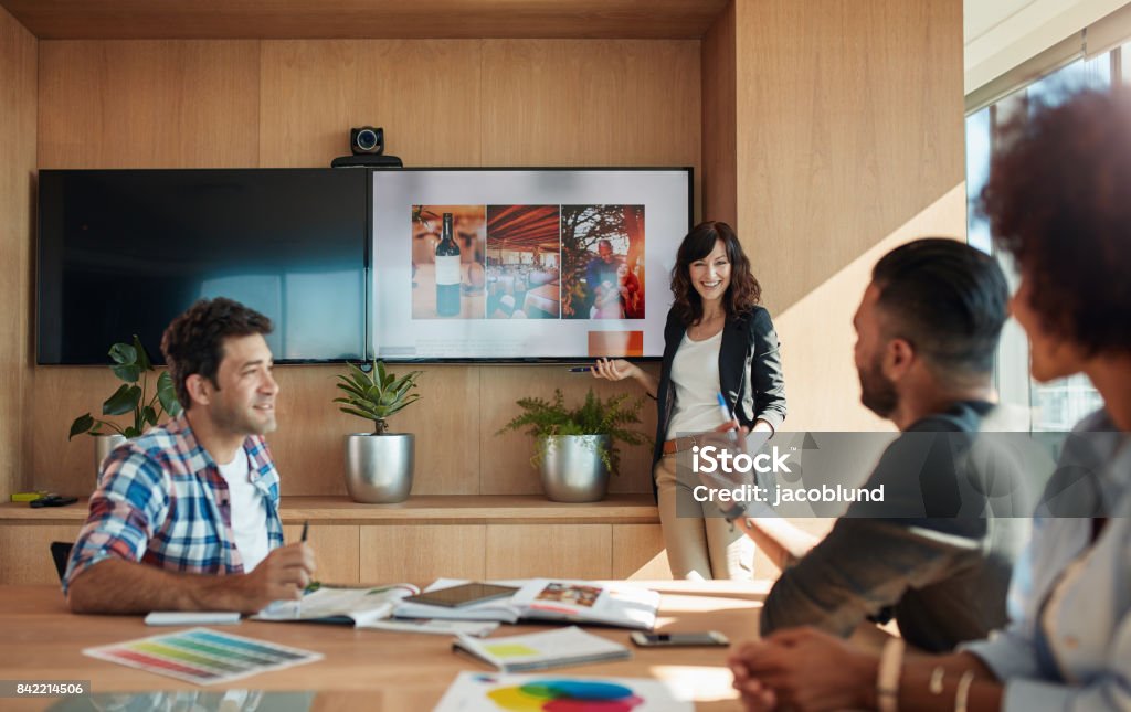 Female coworker making presentation in office Female coworker making presentation during business meeting in office. Group of creative designers discussing new marketing ideas together in boardroom. Advertisement Stock Photo