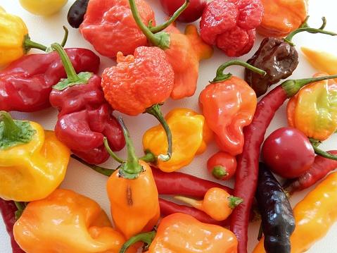 Stack of Red Chili Pepper isolated on plain black background table top view.