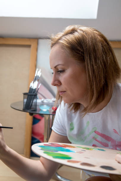 istock Happy young woman paints on canvas 842216854