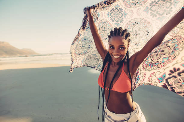 Afro american female standing on the seaside with her scarf. Beautiful woman standing on the beach with fabric.