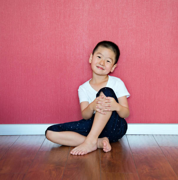 niño sentado en el piso contra la pared - abrazar las rodillas fotografías e imágenes de stock