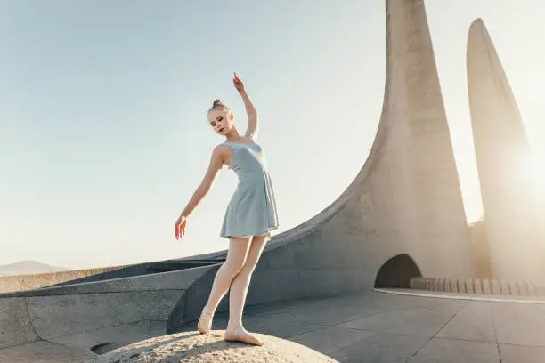 Photo of Female ballet dancer practicing dance moves on a rock