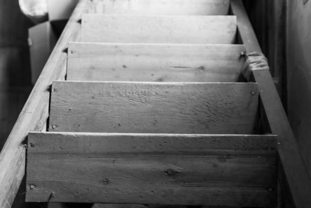 Old dusty wooden loft stairs covered with sunlight. Black and white