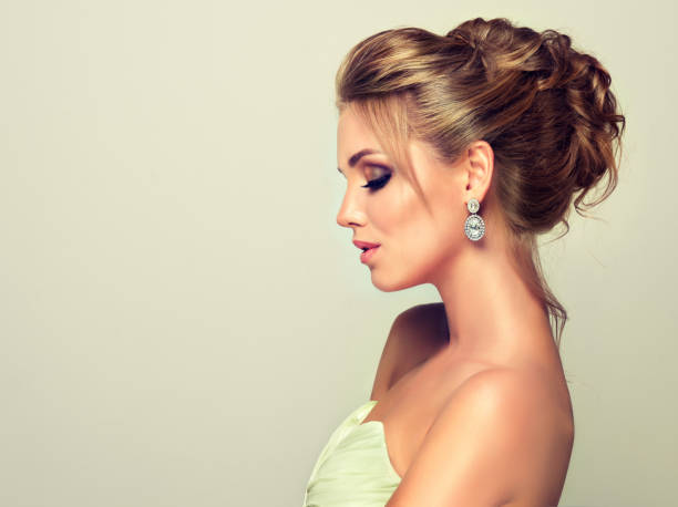 Young and attractive blond model dressed in evening gown and jewelry earings. stock photo