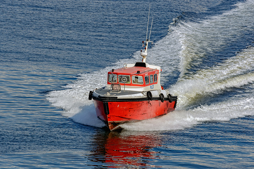 Boat speeding in front of a container ship at the Industrial port of Miami, Florida