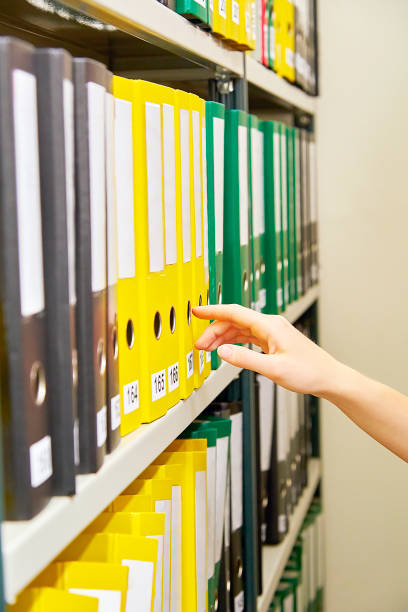 アーカイブし、それらを指している人間の手で黄、緑、黒のファイル フォルダー - ring binder file green document ストックフォトと画像