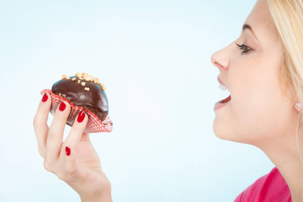 istock Woman holding chocolate cupcake about to bite 842273974
