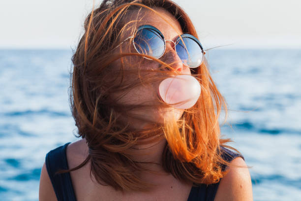 Young woman blowing bubble gum by the sea