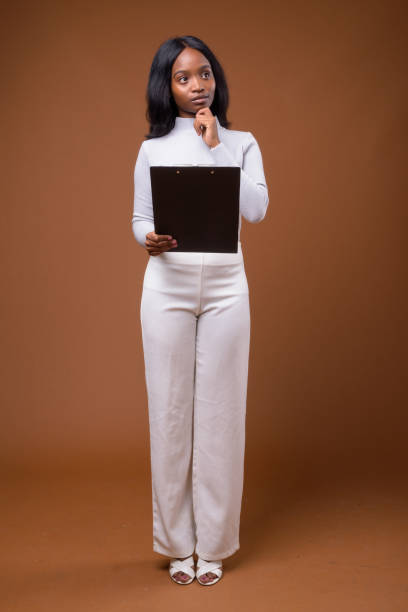 photo de studio de jeune belle femme d’affaires africaine zulu porter le chandail à col roulé sur fond coloré - full length clipboard african ethnicity black photos et images de collection