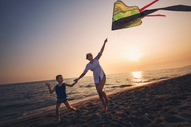 istock Mother and child flying kite at beach 842285334