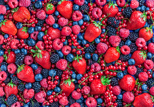 Berries overhead large closeup colorful assorted mix of strawberry, blueberry, raspberry, blackberry, red curant in studio on dark background in studio