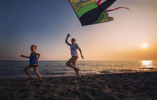 istock Mother and child flying kite at beach 842289494