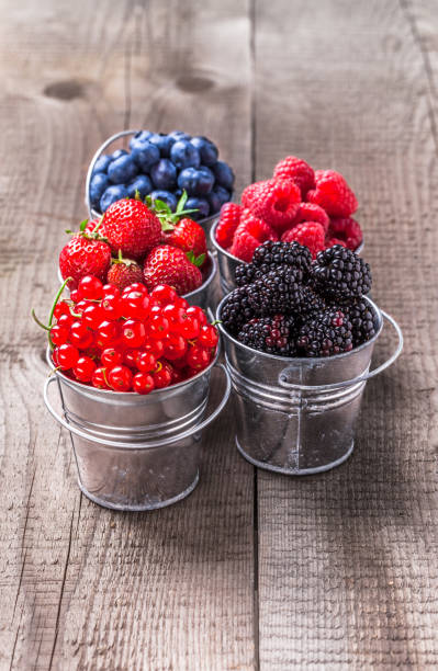 istock Berries colorful assortment in tin cans on rustic wooden table 842289670