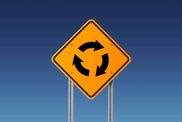 Yellow roundabout traffic sign on blue sky. Going in circles and indecision concept. Horizontal composition with copy space. Clipping path is included.