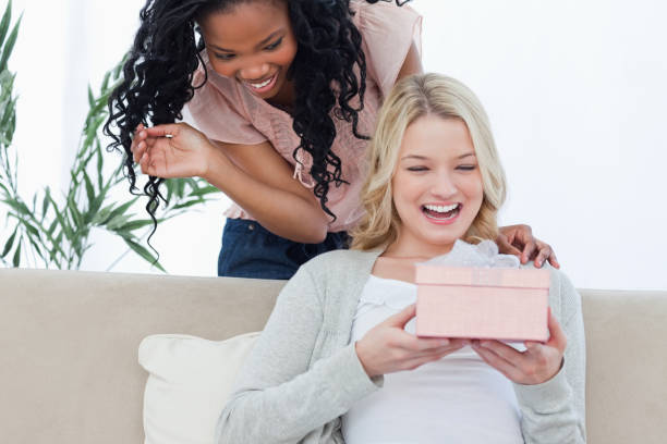 istock A surprised woman is holding a present with her friend standing behind her 842306890