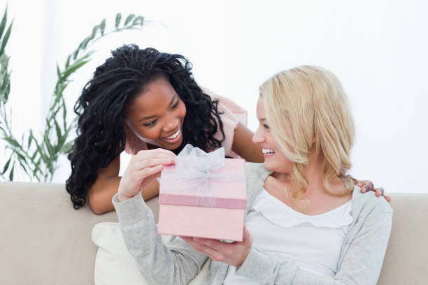 istock A woman holding a present is smiling at her friend 842308064