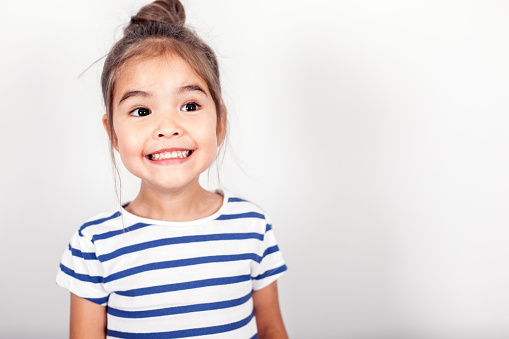 Funny small girl on the grey light background in the studio.