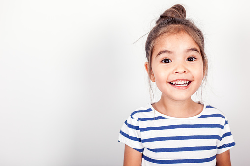 Redhead smiling little girl model posing in white t-shirt on grey studio background