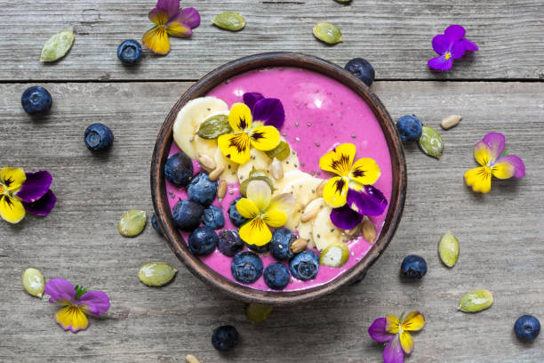 Smoothie bowl with fresh berries, nuts, seeds and flowers