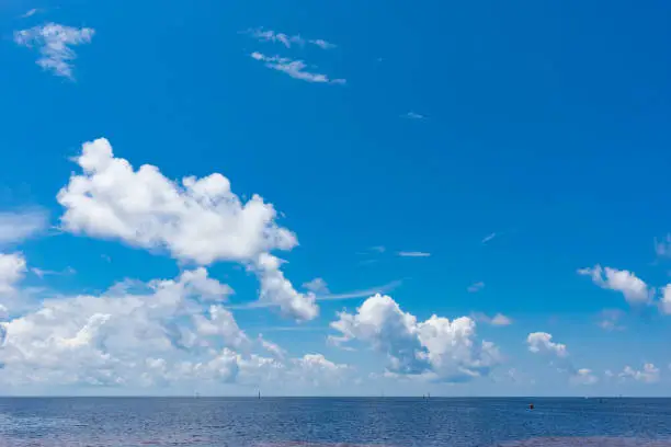 A blue sky and fair weather clouds over the water of the Gulf of Mexico.