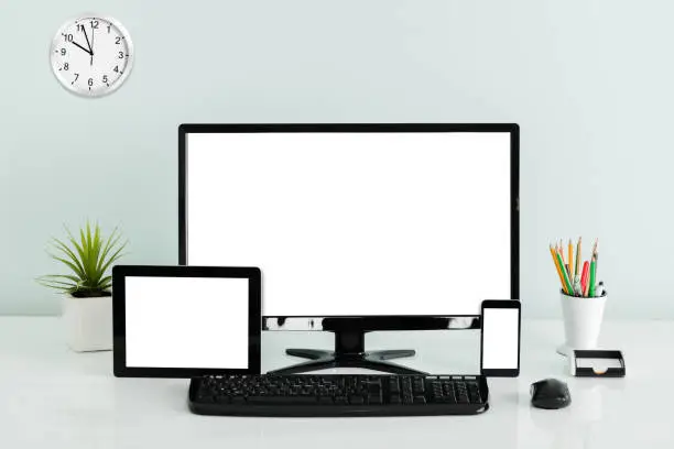 Computer Desktop With Digital Tablet And Mobilephone Showing Blank Screen On Office Desk
